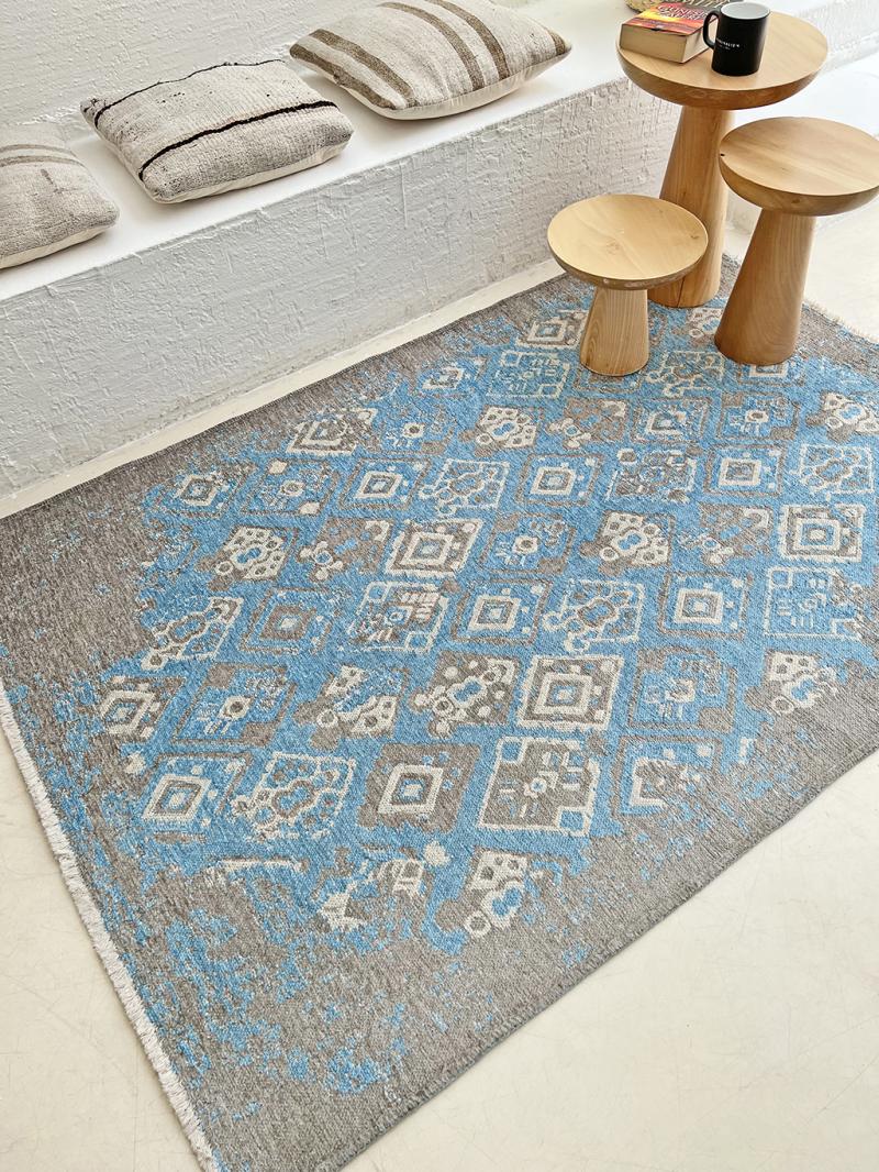 Overhead view blue gray patterned rug with wooden side tables and pillows