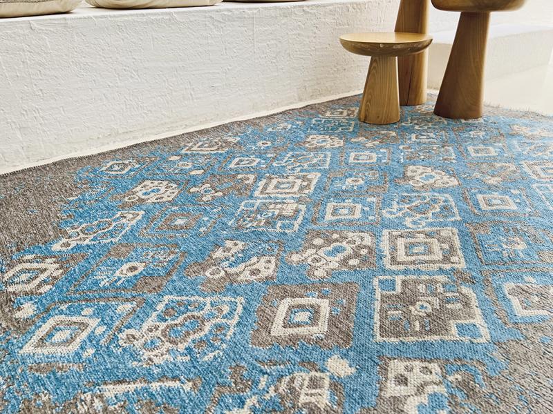 Blue and gray patterned area rug with two wooden side tables