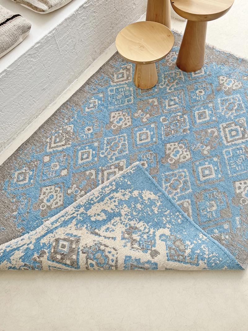 View of blue and gray patterned rug with two wooden side tables