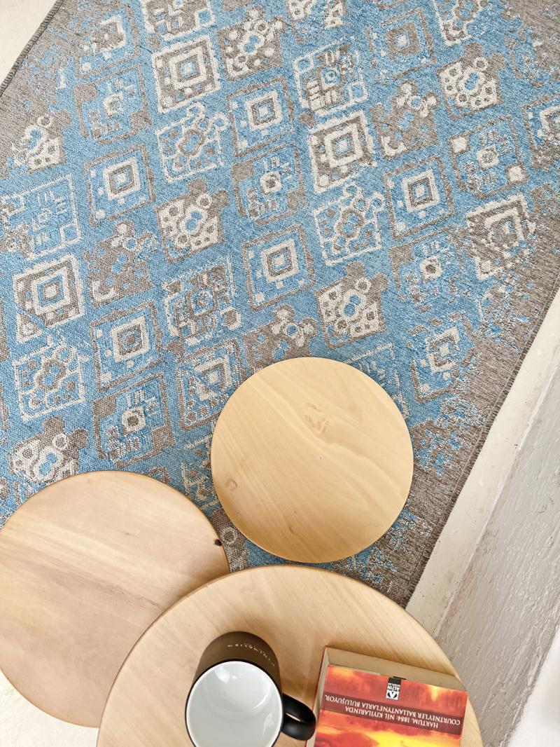 Overhead view of blue patterned rug and three round wood tables