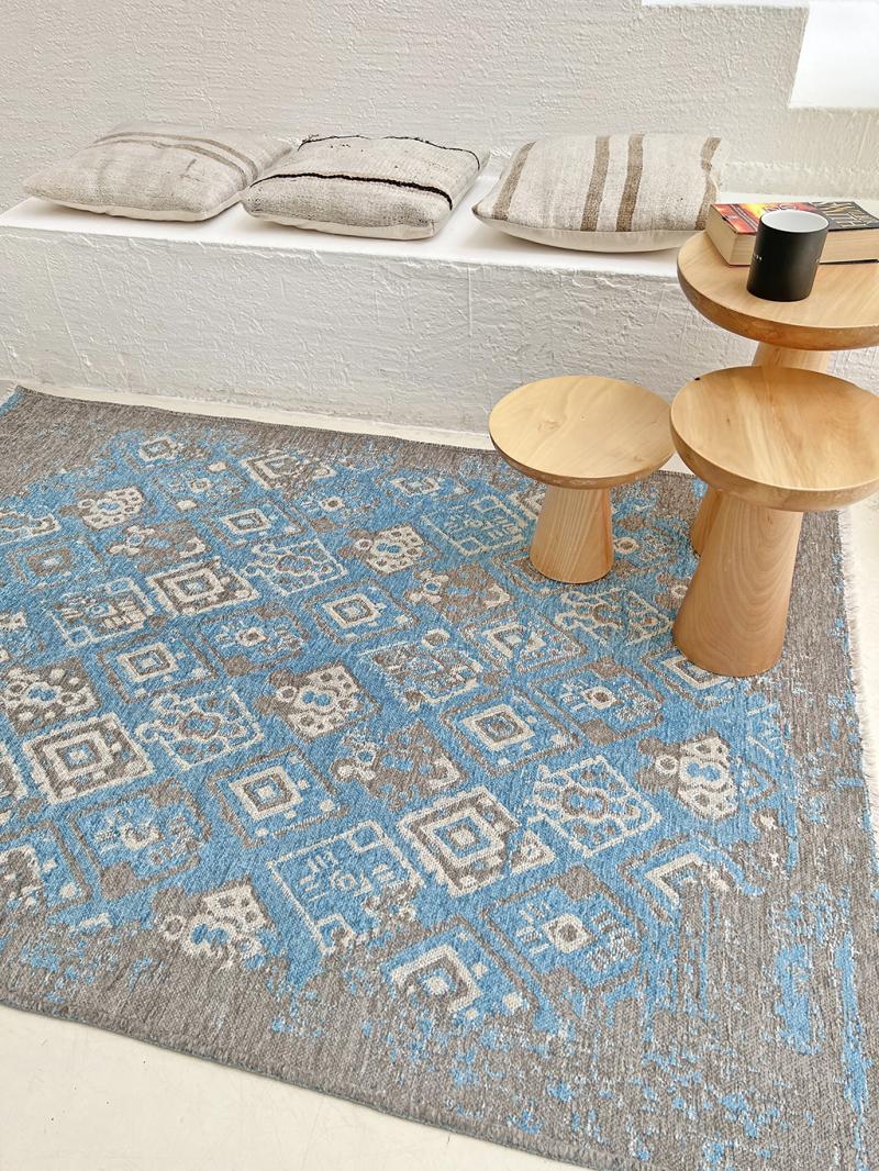 Blue gray patterned area rug, three wooden side tables, pillows on ledge