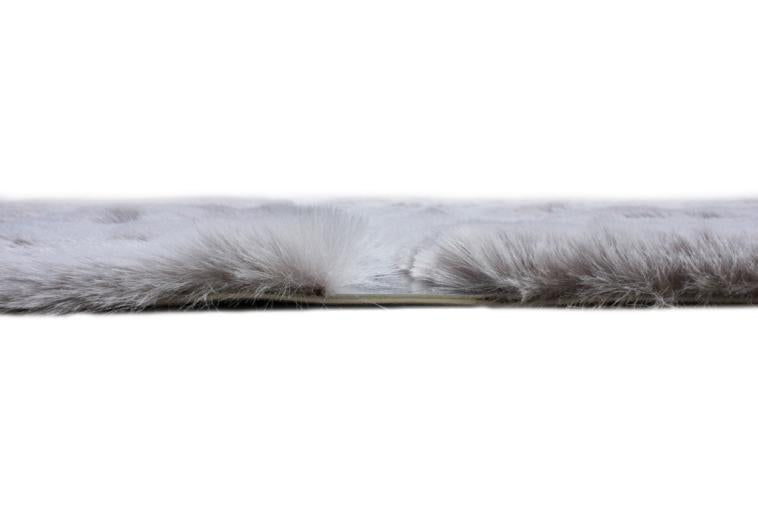 Angled view of Rabbit Fur Rug under a coffee table, highlighting its plushness in a contemporary setting.