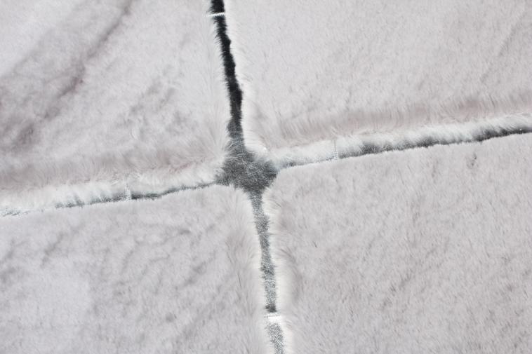 Rabbit Fur Rug placed in a serene bedroom, adding warmth and elegance with its gray and silver hues.