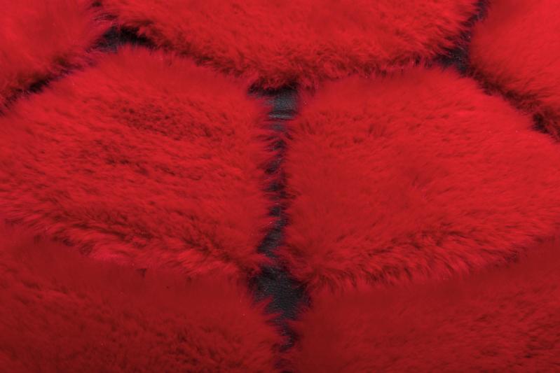 Angled view of Rabbit Round Fur Rug under a contemporary coffee table, showcasing its bold design in a unique setting.