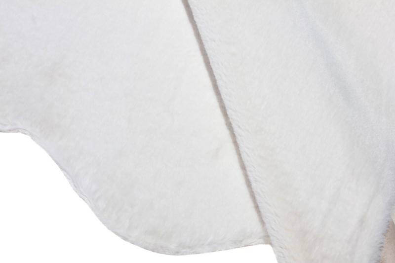 Angled view of cream sheep-textured rabbit fur rug under a coffee table, showcasing its soft texture.