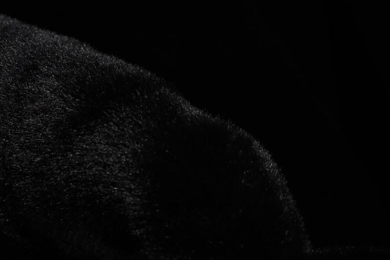 Angled view of black sheep-textured rabbit fur rug under a coffee table, showcasing its stylish appearance in a modern setting.