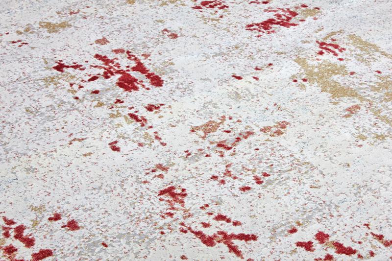 Close up view of white rug with red and gold abstract pattern
