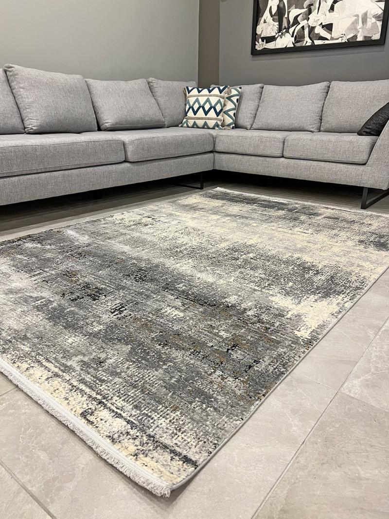 View of gray abstract area rug on tile floor with sectional sofa