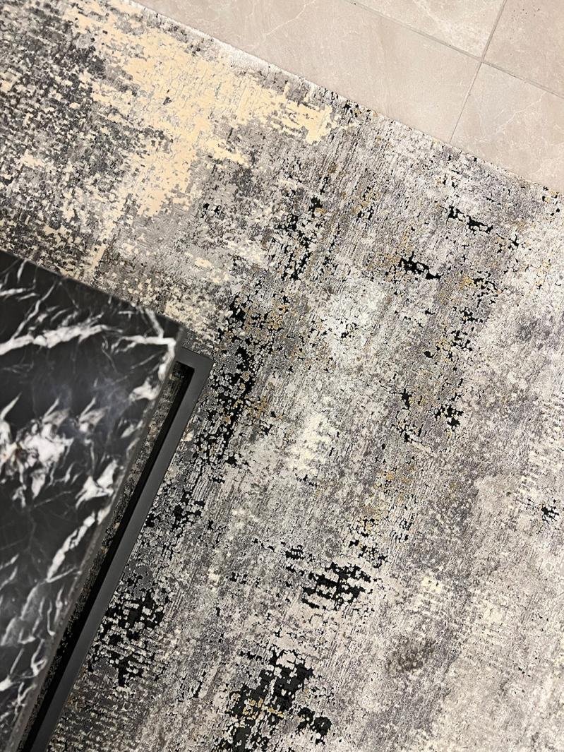 Overhead view of abstract gray rug and black marble table edge.