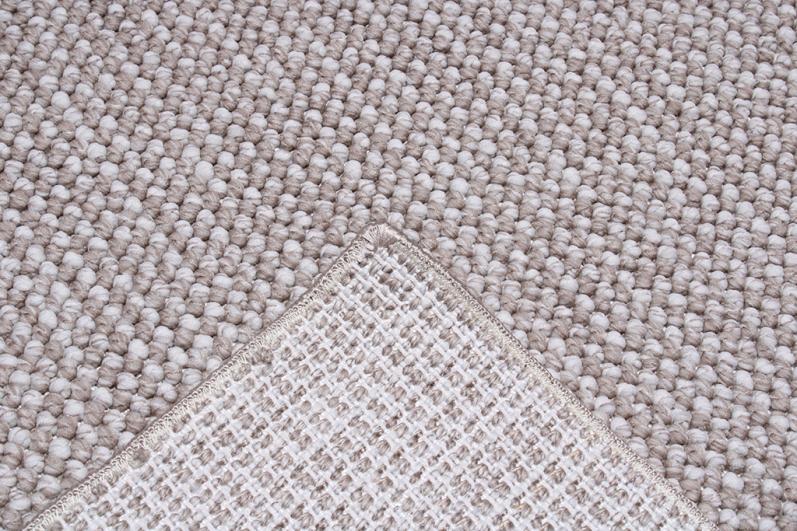 Close-up view of beige textured rug showing backing material