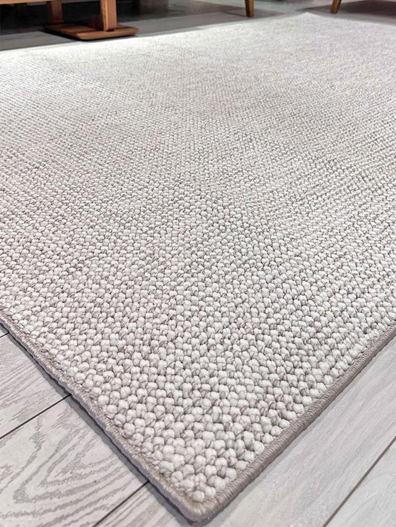 Close up view of light gray textured area rug on wood floor
