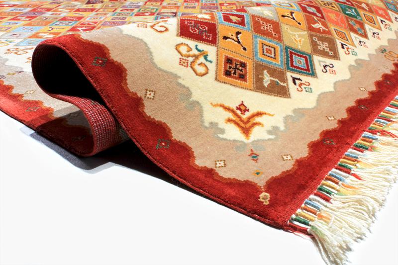 Close up view of colorful patterned rug with fringe and rolled edge
