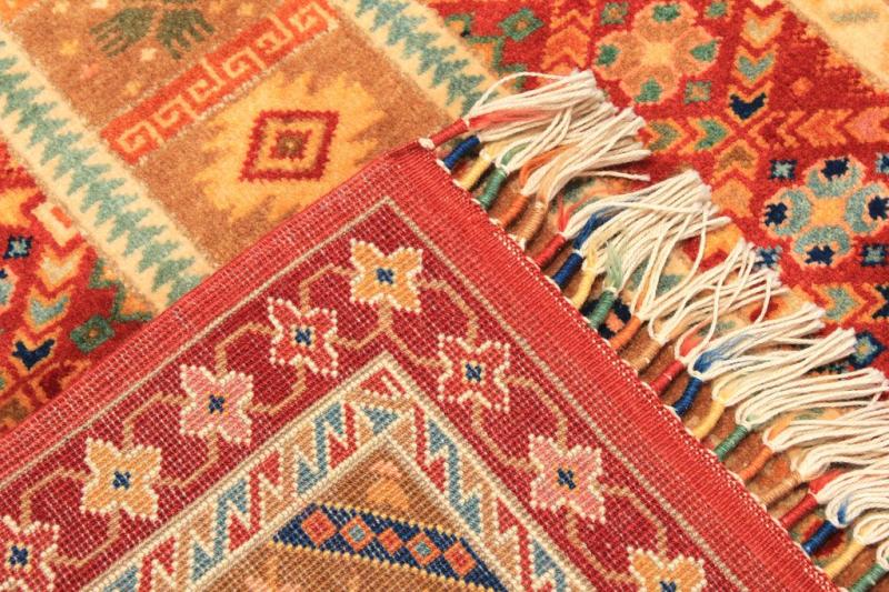 Close up view of colorful patterned rug with fringe tassels showing fold.