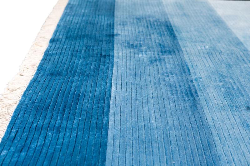 Close up view of blue striped rug with fringe