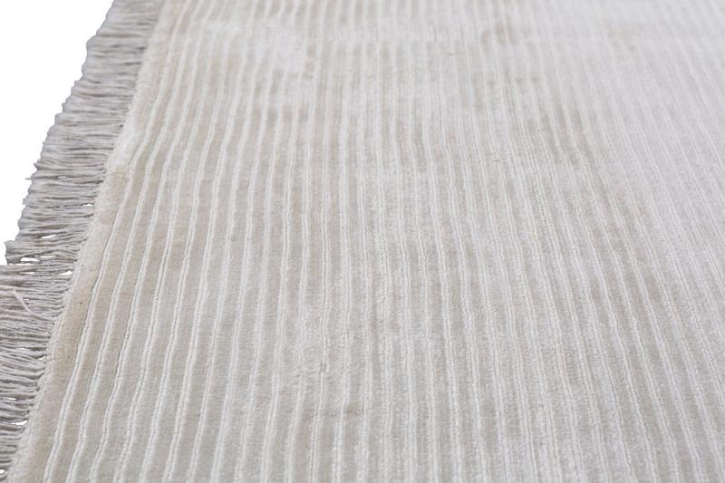 Close-up view of white striped rug with fringe edge