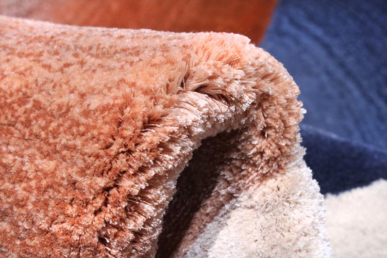 Angled view of Circle Tufted Rug under a glass coffee table, illustrating its ability to complement upscale decor.