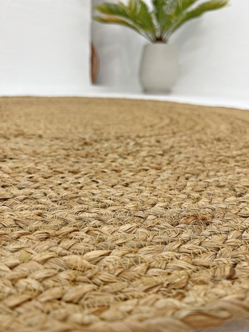Close up view of braided natural fiber rug with plant in background