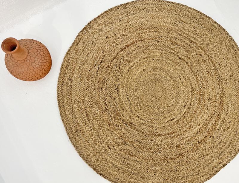 Round braided jute rug and textured terracotta vase decor