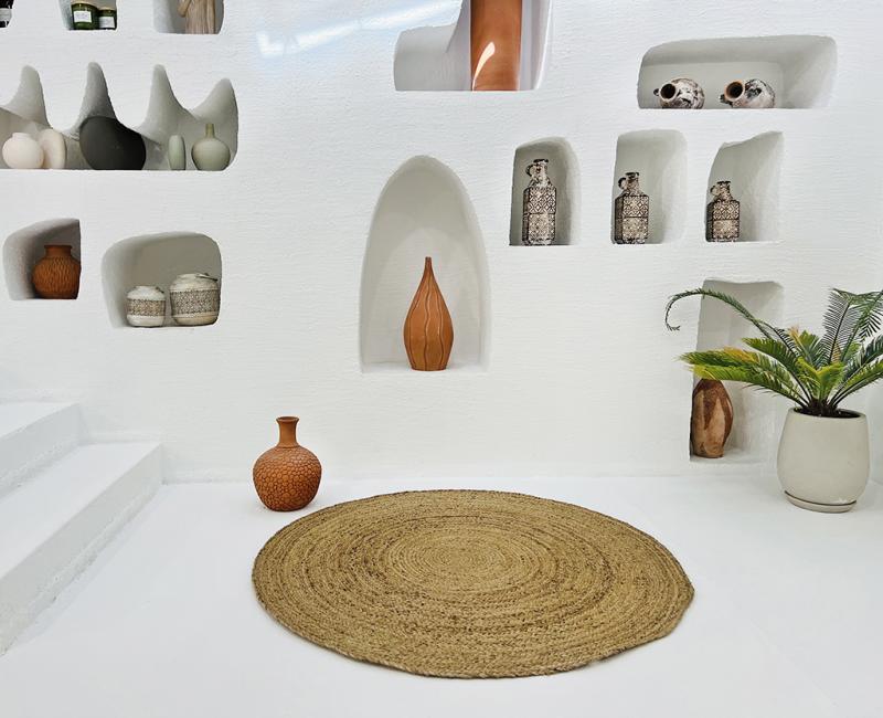 White wall niches displaying vases, pottery, and a round jute rug