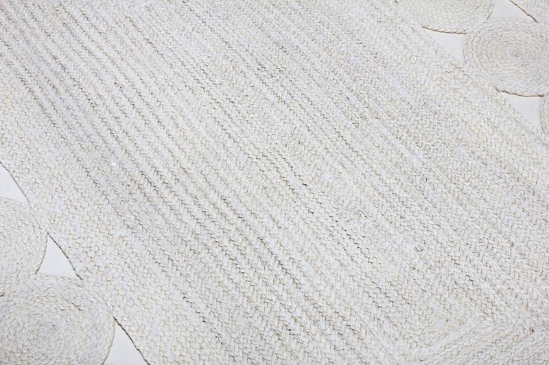 Overhead view of white braided jute rug with circular accents
