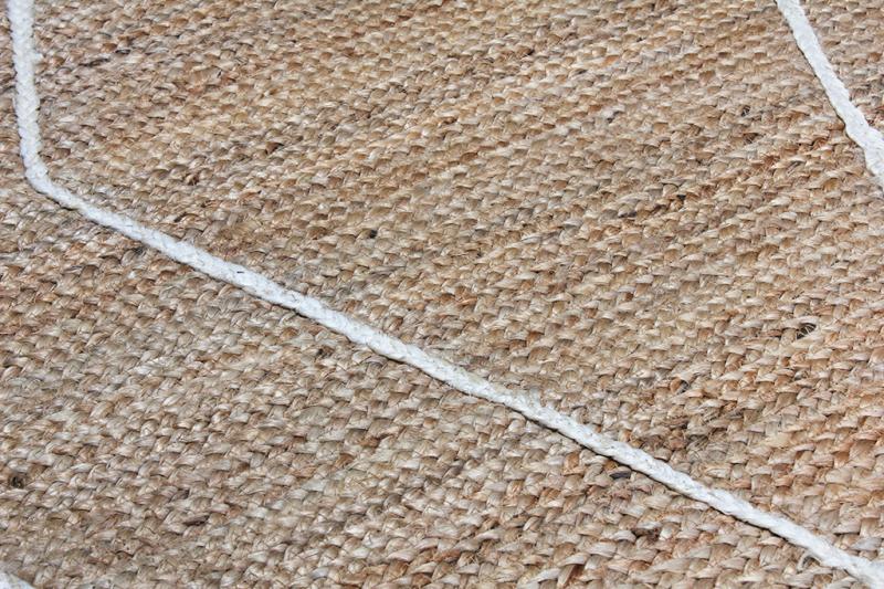Close up view of woven jute rug with white rope detail