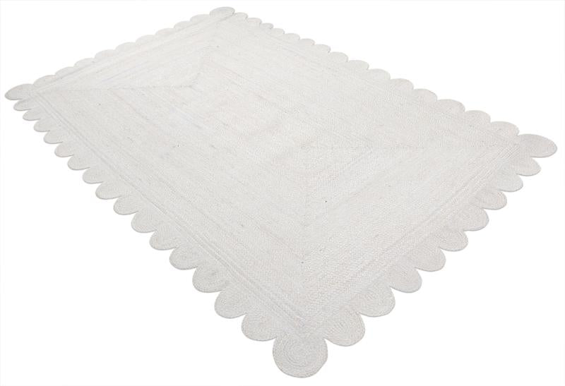 White scalloped jute area rug on white background.