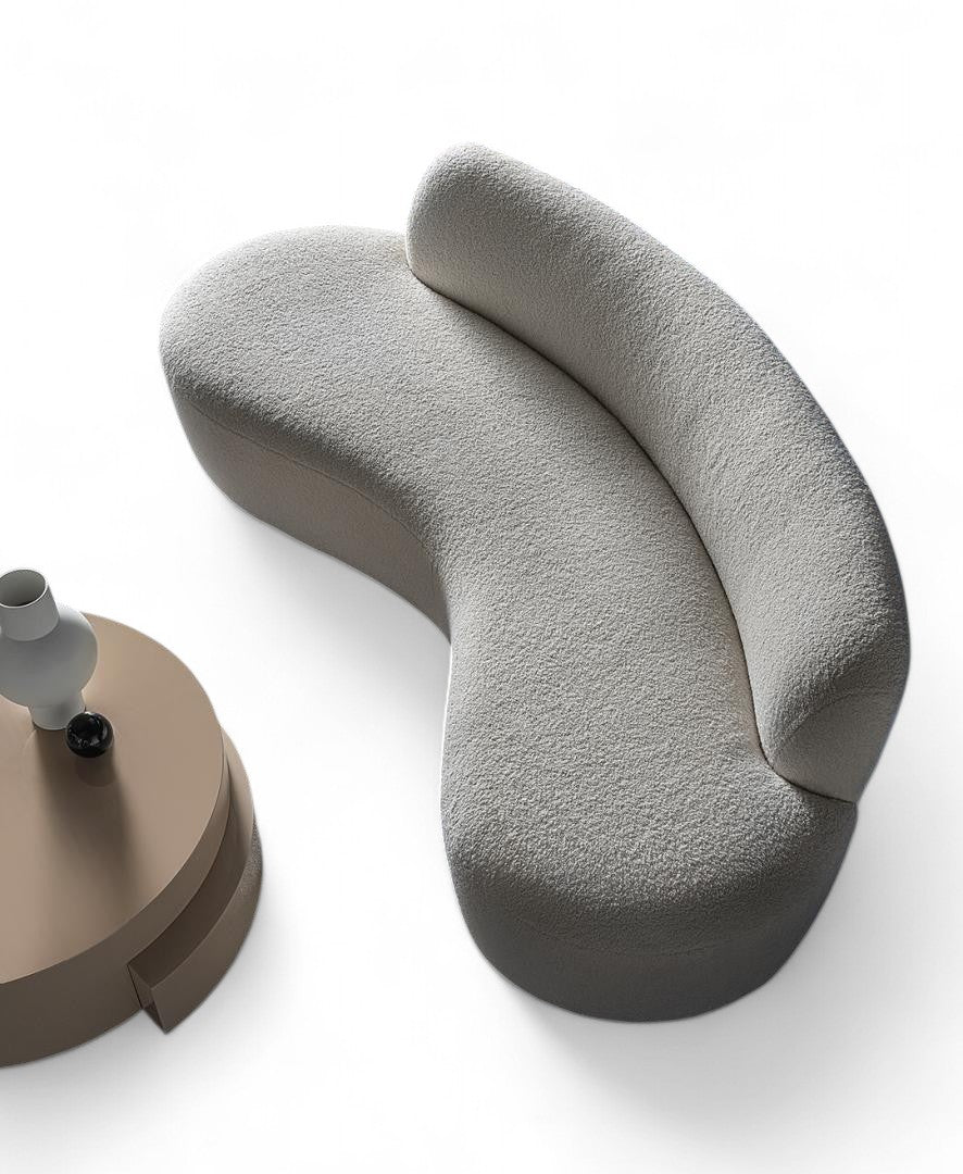 Overhead view curved gray boucle sofa beside round brown table