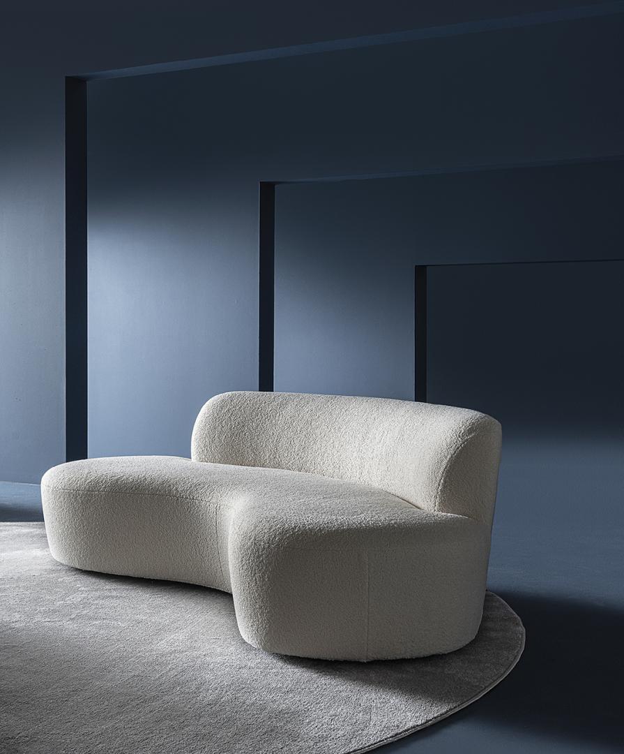  Modern living room featuring the Casamilano Curvy Mono sofa, a curved couch with textured upholstery, set against a deep blue wall