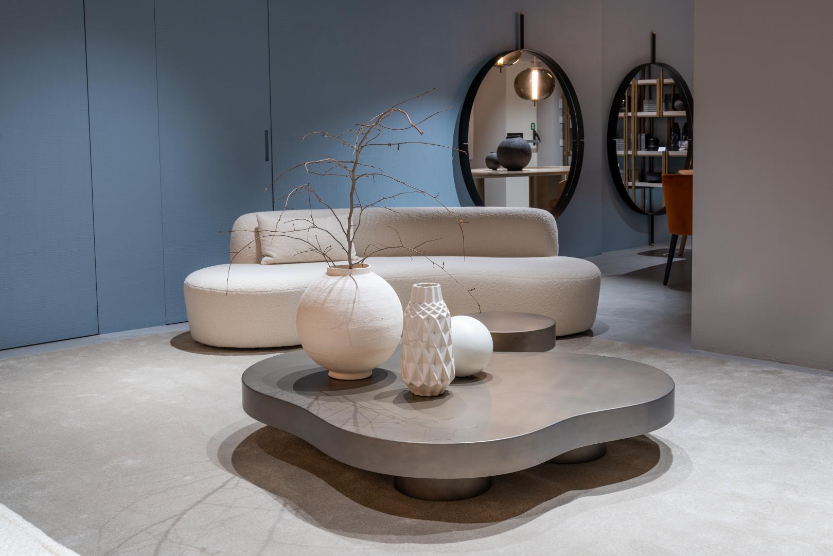  Modern living room featuring a Curvy Mono sofa by Casamilano, metal coffee table, vases, round mirrors, and blue wall paneling
