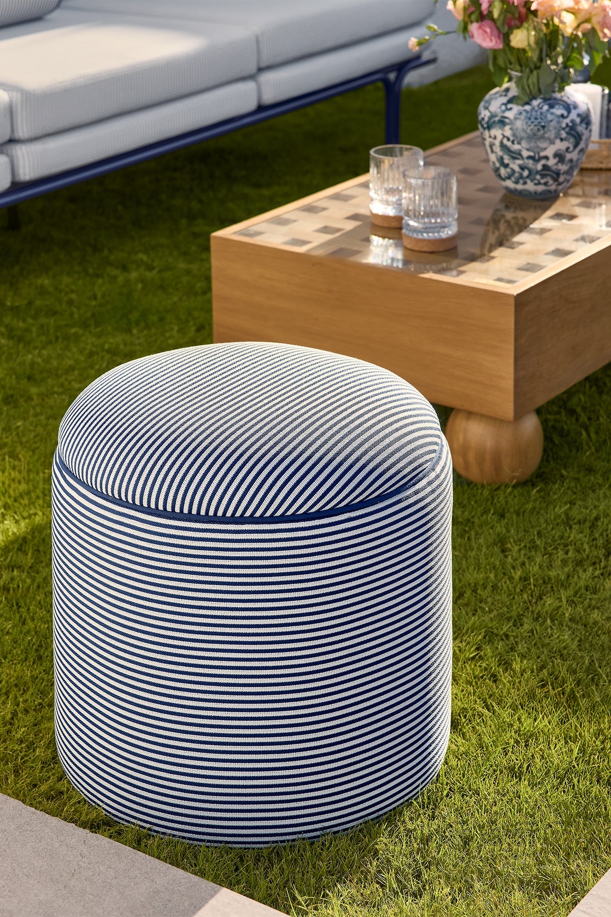 Bari Outdoor Pouf in blue-striped performance fabric on outdoor grass.