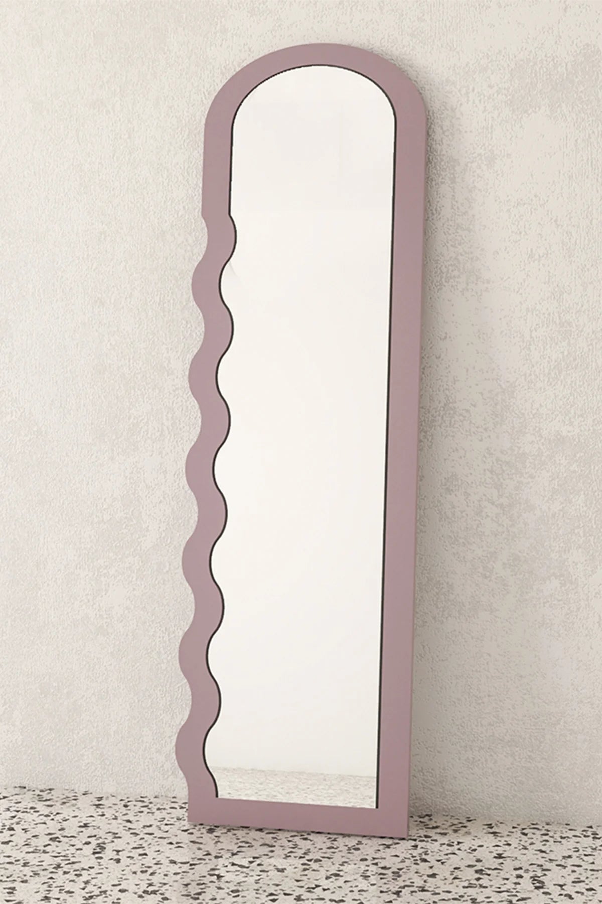 Full-length mirror with a decorative dusty mauve frame on a textured surface.