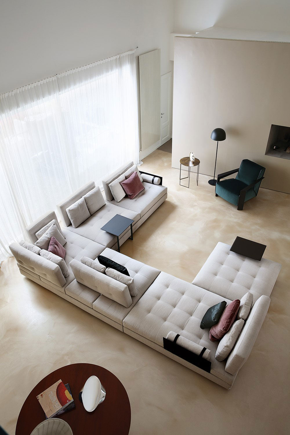 Overhead view of large light gray modular sectional sofa in living room with armchair and tables.
