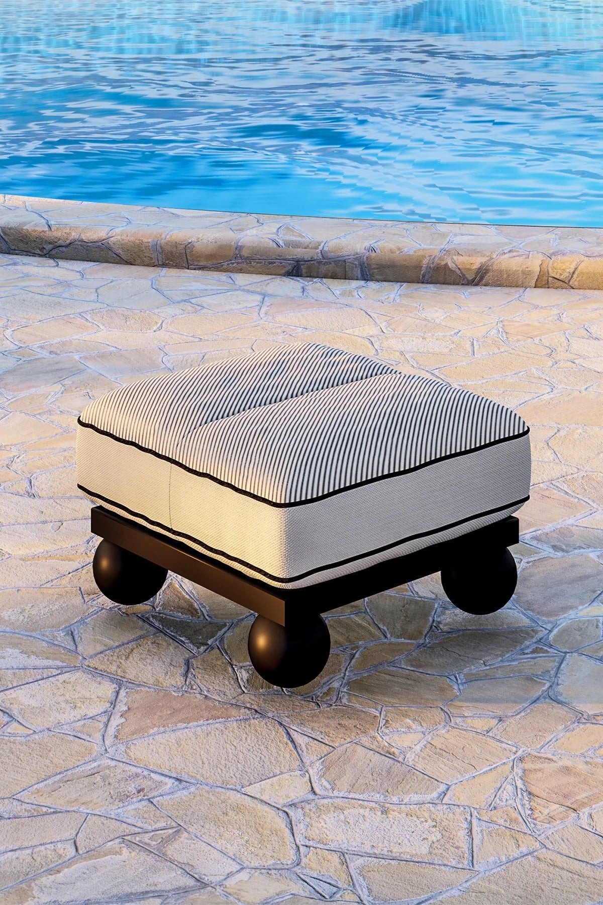 Decorative ottoman with striped cushion on a stone patio by a pool