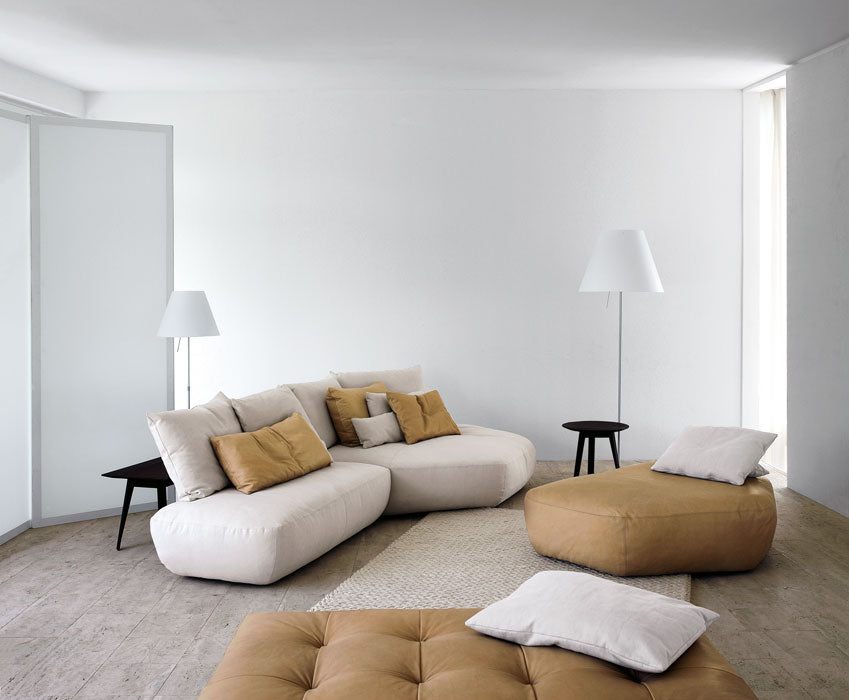 White modular sofa with tan leather ottomans and floor lamps