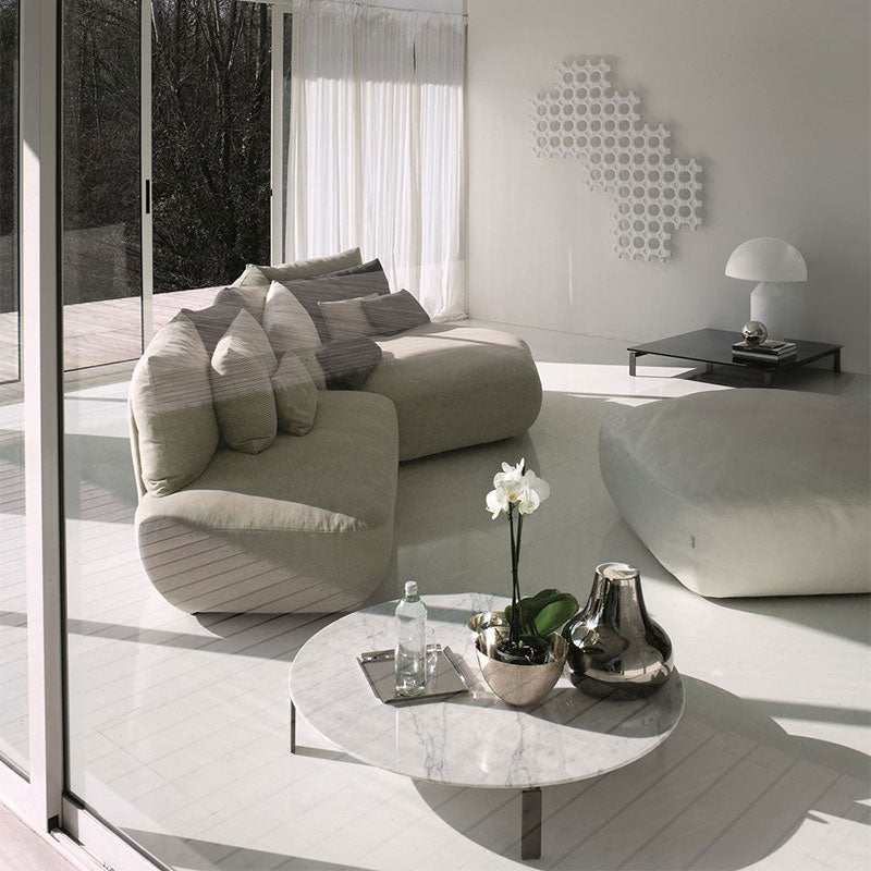 Modern living room with curved sectional sofa, marble coffee table, and white wall decor