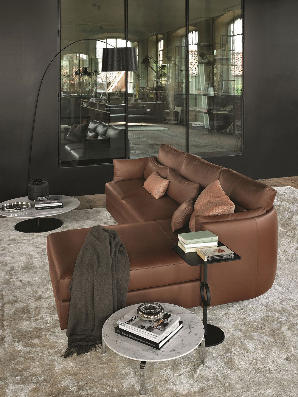 Industrial loft setting with brown leather sectional sofa and marble side tables.
