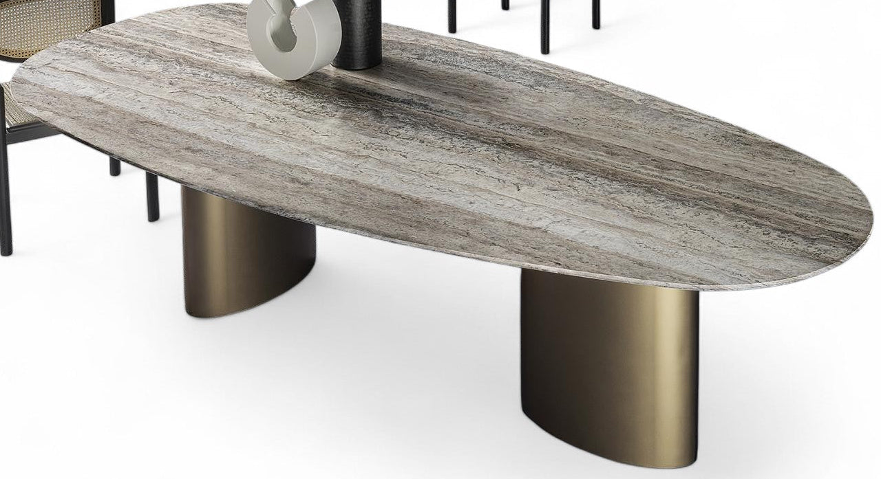 Studio shot of oval stone dining table with bronze base, two chairs, and decor.