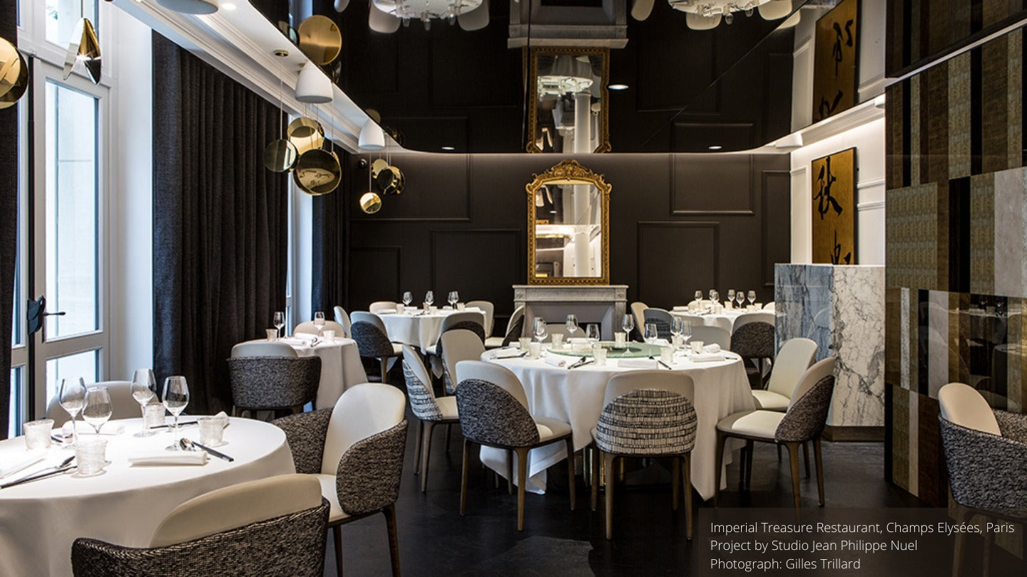 restaurant interior, round dining tables, upholstered chairs, gold lighting, mirror