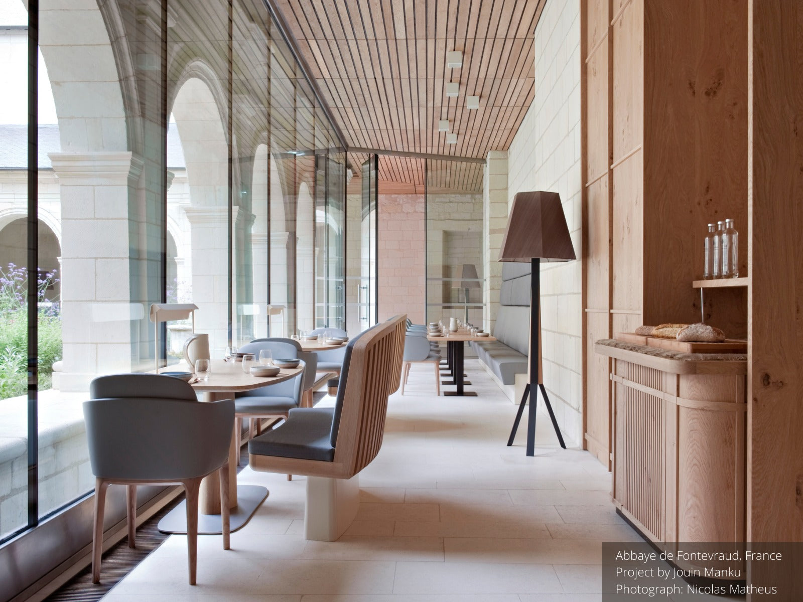 Restaurant interior with wood paneling, wood chairs, tables, and floor lamp.