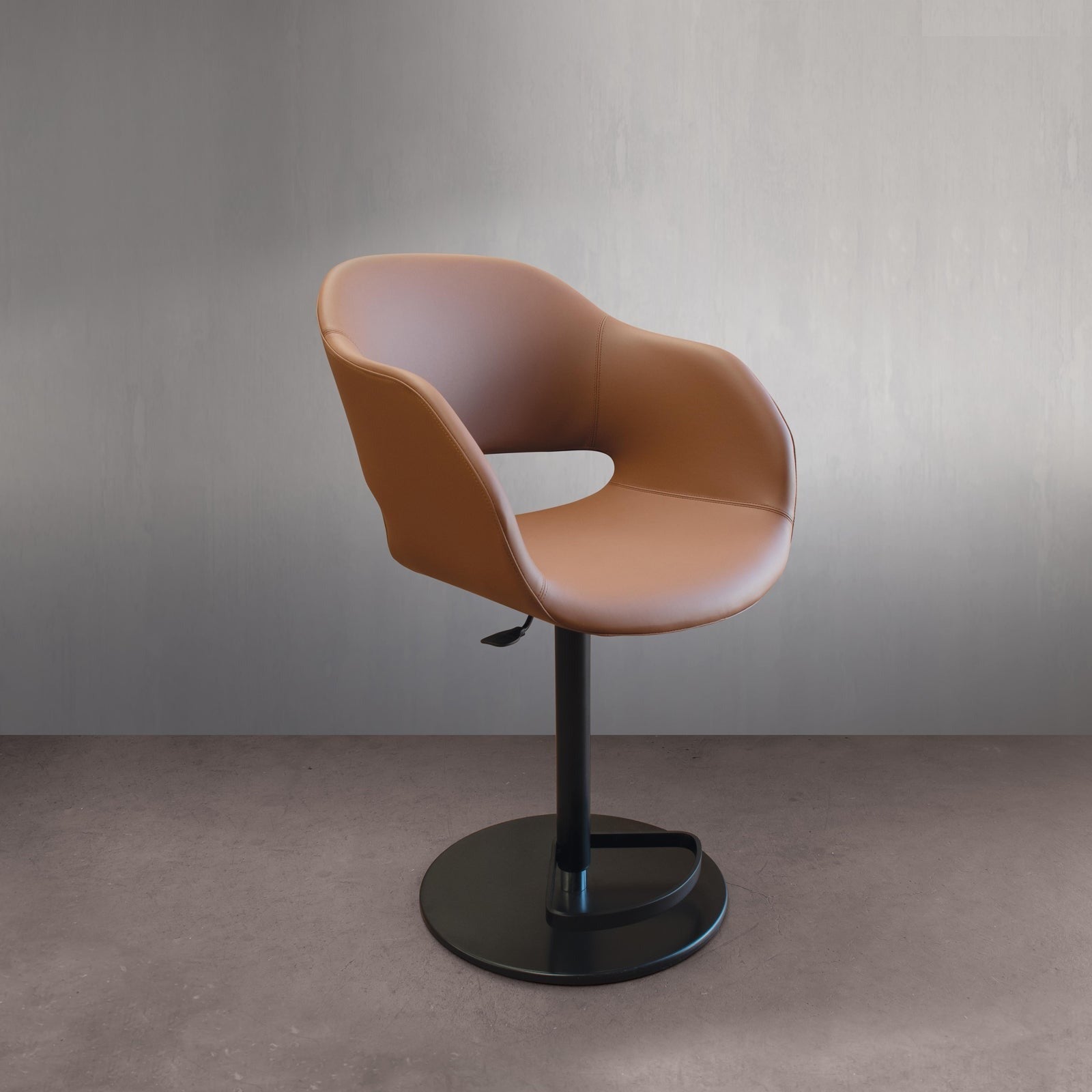 Studio view of brown leather swivel bar stool with black base. 