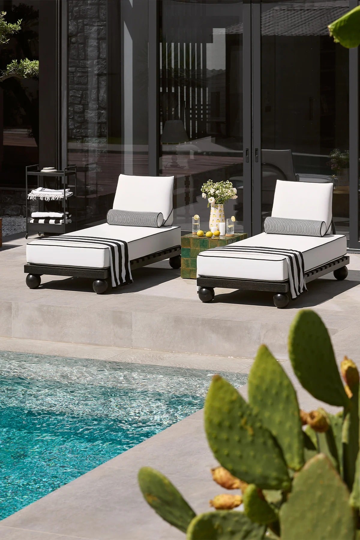 Two outdoor lounge chairs by a pool with decorative elements.