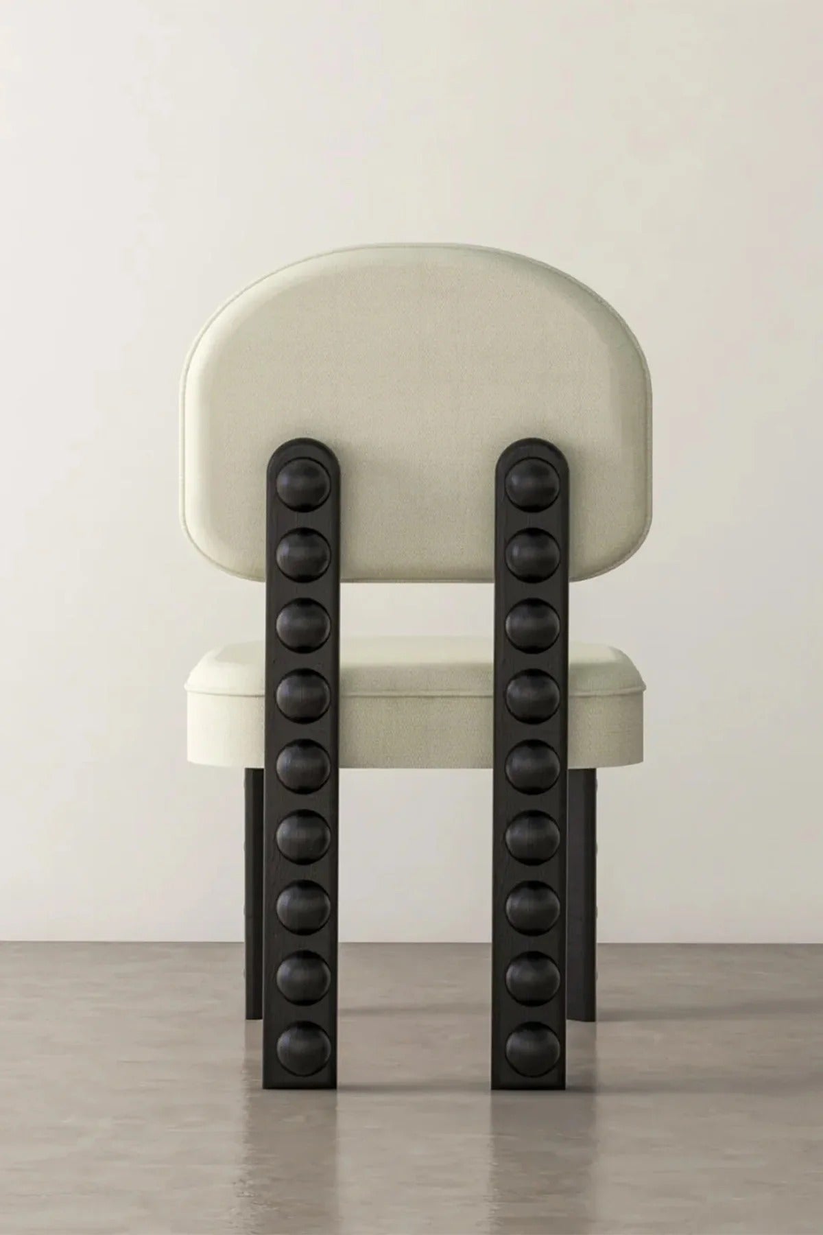 View of beige upholstered chair with black studded back supports on floor. 