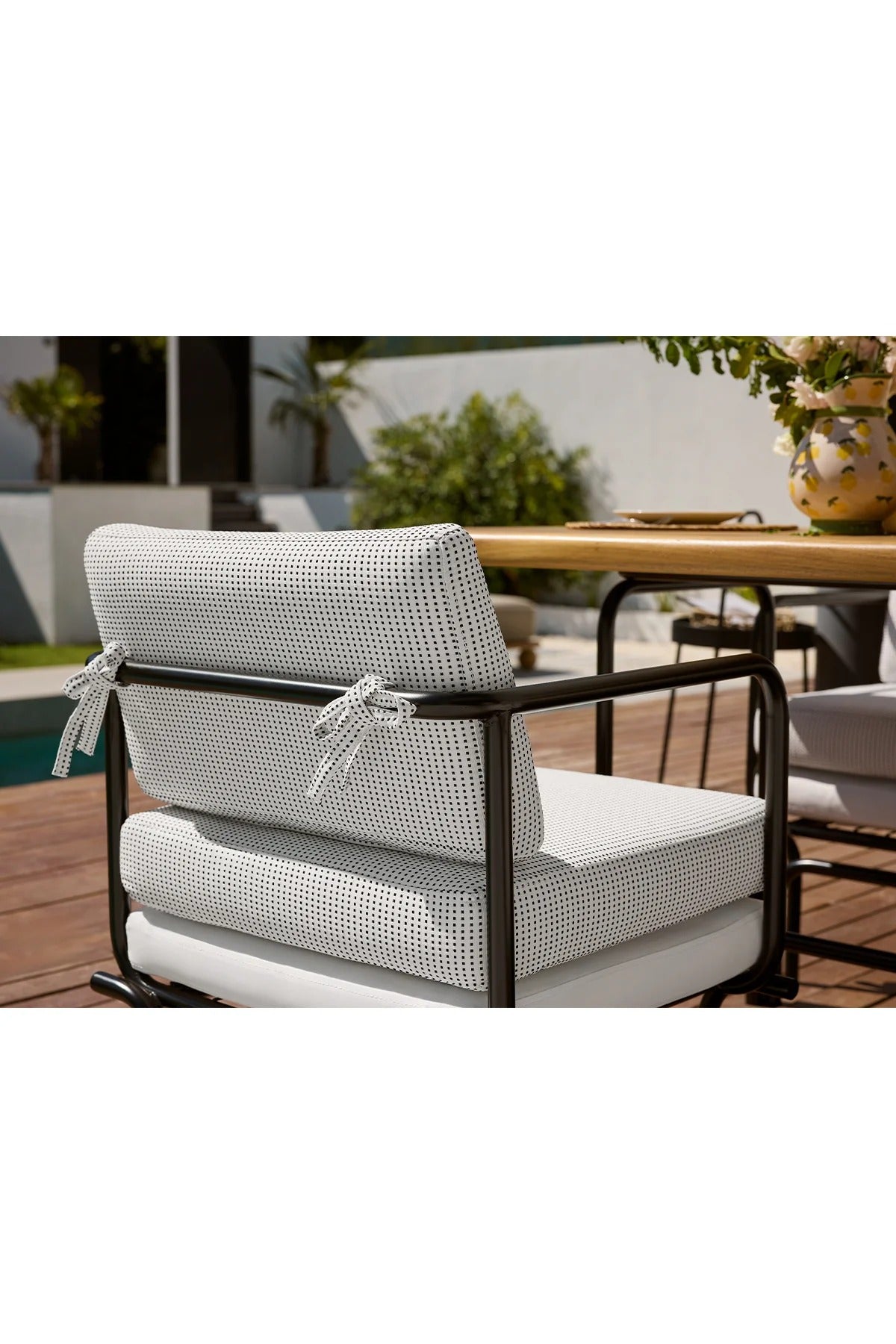 Outdoor chair with cushions on a patio with a pool in the background